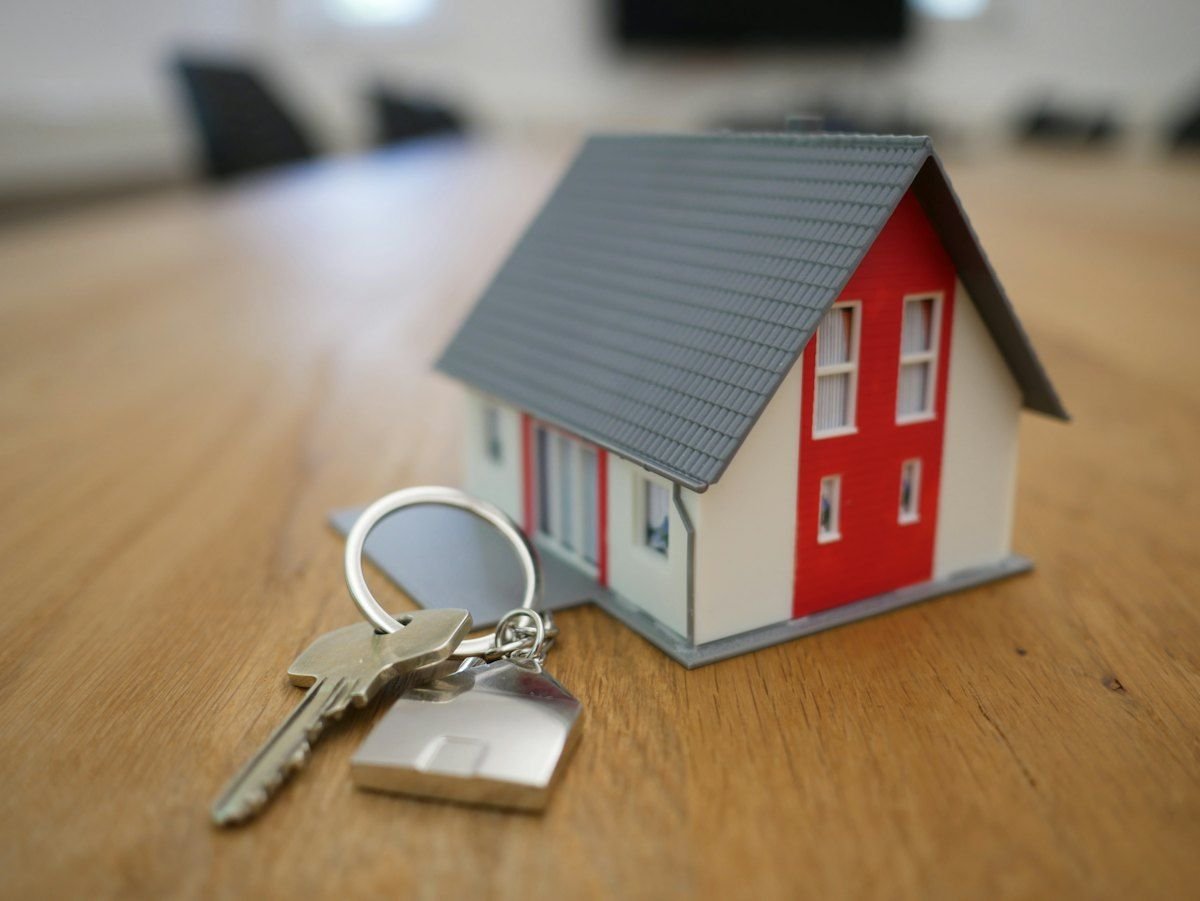 Miniatura de casa com chaves sobre a mesa